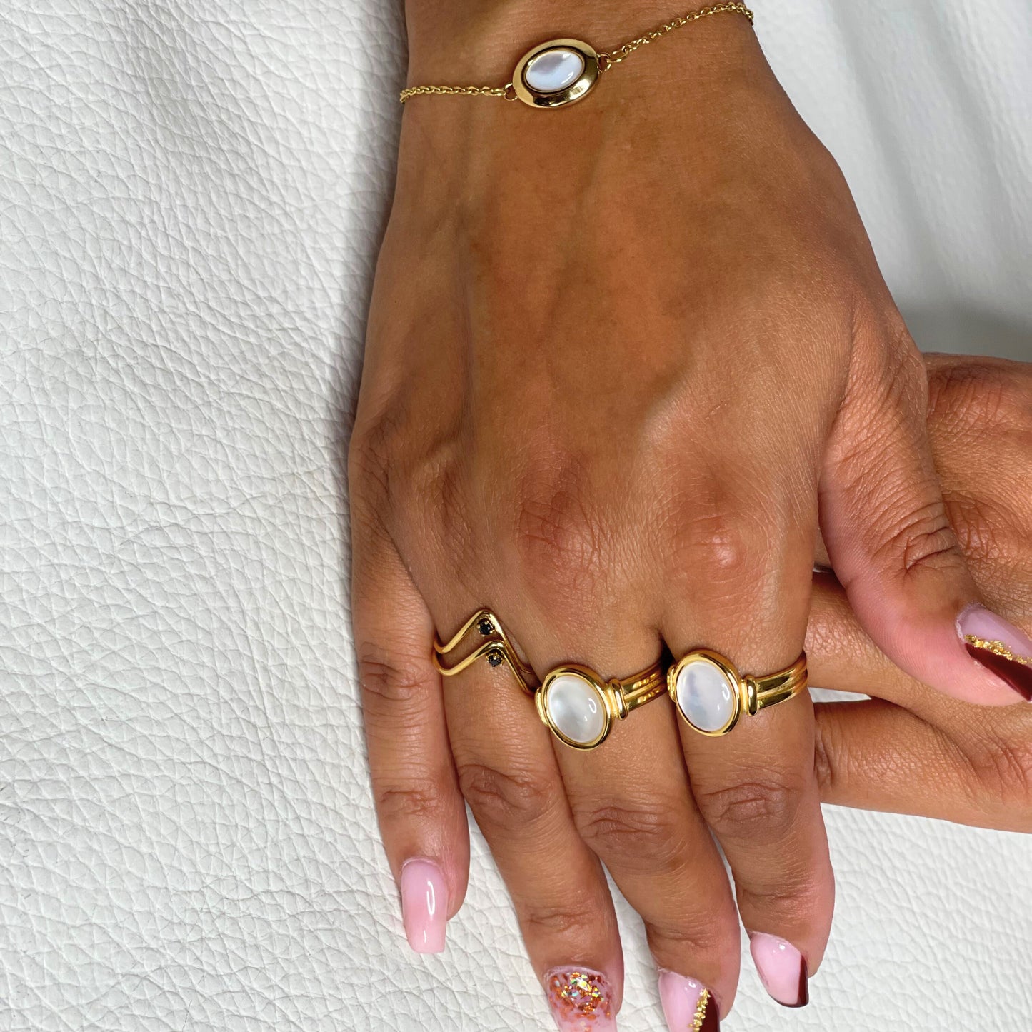 Bague Octavia portée avec élégance, assortie à un bracelet en plaqué or et pierre nacrée. Bijou raffiné en acier inoxydable, idéal pour toutes occasions.