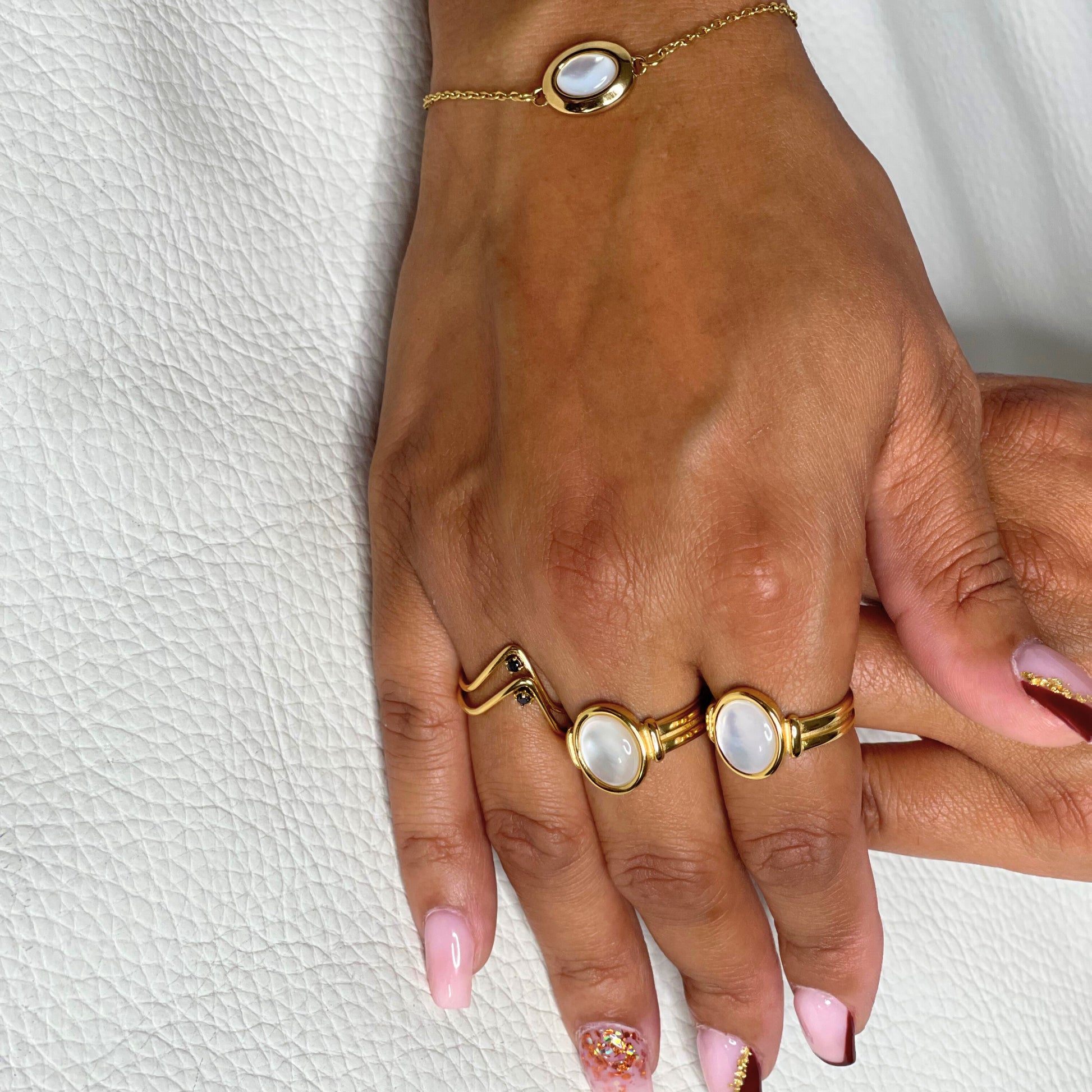 Bague Octavia portée avec élégance, assortie à un bracelet en plaqué or et pierre nacrée. Bijou raffiné en acier inoxydable, idéal pour toutes occasions.